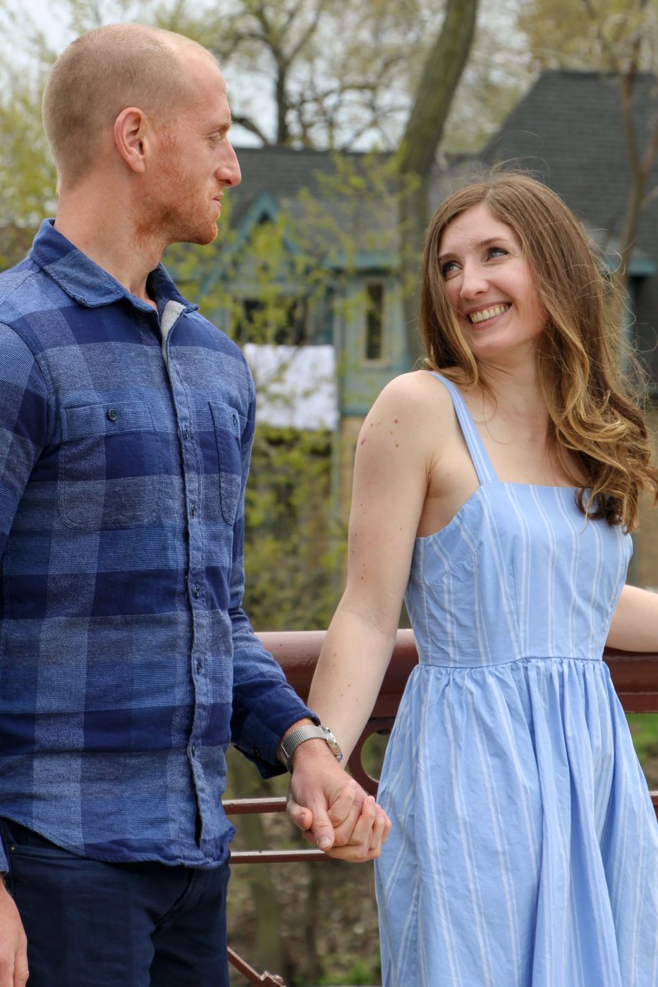 Engaged couple holding hands on a wooden bridge in autumn